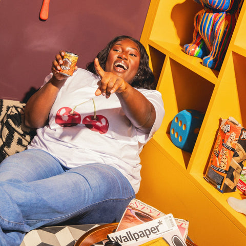 Someone smiling and laughing holding a can of GATHER with games in the background. 