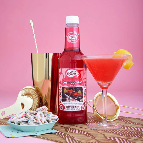 A bottle of Master of Mixes Cosmopolitan cocktail mixer, with a Cosmopolitan cocktail next to the bottle.