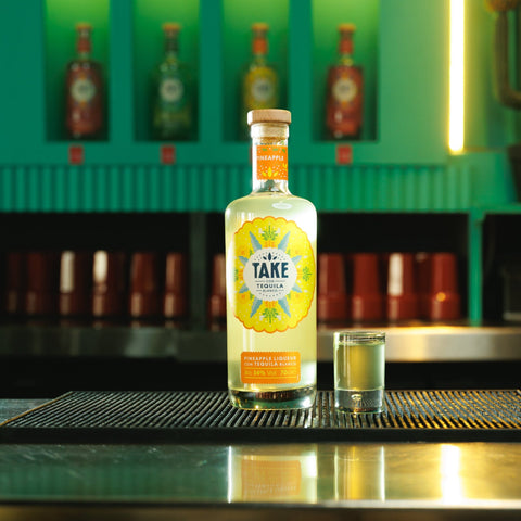 Bottle of 'Take' on a bar with a colorful background