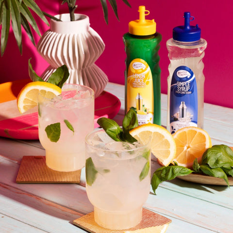 Two cocktails made with Master of Mixes Cocktail Essentials Lemon Juice and Simple Syrup, with the Master of Mixes Cocktail Essentials placed beside the cocktails. 
