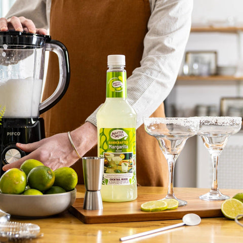 A person preparing frozen margaritas using Master of Mixes Margarita cocktail mixer and Master of Mixes salt for the glasses. 