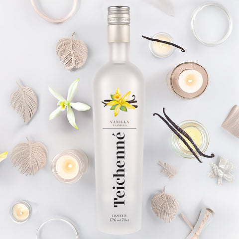 Teichenné vanilla liqueur bottle surrounded by vanilla beans and candles on a light background