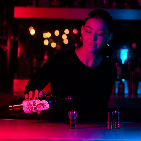 Someone pouring an alcoholic shot of Nottari Nero Sambuca. 