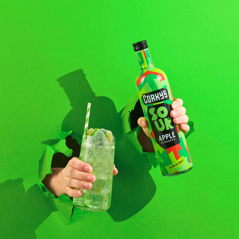 Bottle of Corky's sour apple schnapps and a drink of Corky's coming through a bright green background. 