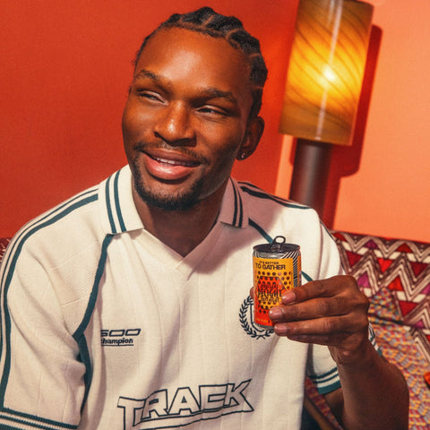 A person smiling holding a can of GATHER. 