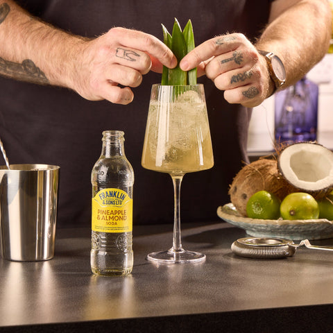 Someone making a drink with Franklin & Sons pineapple & almond soda, a premium soft drink & mixer. 