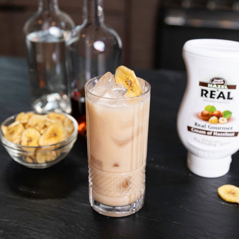 A hazelnut drink made using Re'al Cream of Hazelnut syrup, with the bottle of Re'al syrup placed next to the drink. 