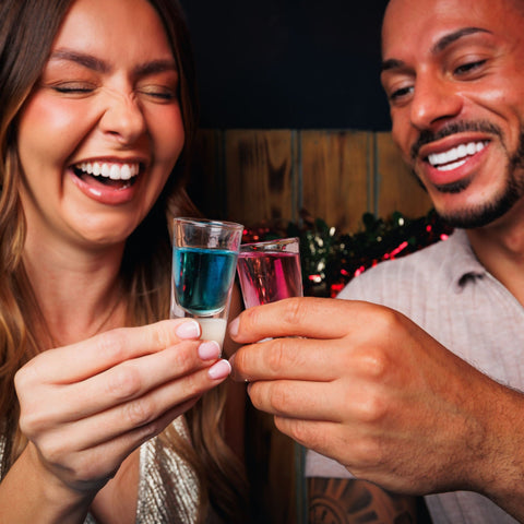 Two people smiling and having a shot of Corky's sour schnapps. 