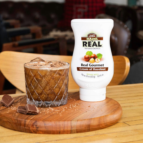 A hazelnut and chocolate cocktail made using Re'al Cream of Hazelnut syrup, with the Re'al syrup placed next to the cocktail. 