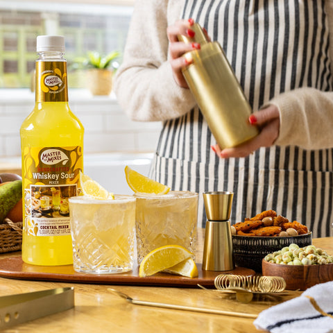 Someone making two whiskey sours using Master of Mixes whiskey sour mixer, a perfect bar ingredient for cocktails or mocktails.  