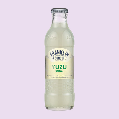 Glass bottle of Franklin & Sons Ltd Yuzu Soda on a light purple background