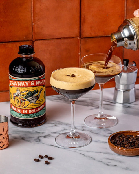 Someone pouring an espresso martini made with Shanky's Whip next to a bottle of Shanky's Whip.