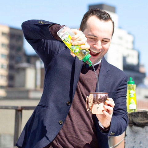A man making a Mule cocktail using Master of Mixes Cocktail Essentials Sweetened Lime Juice syrup . 