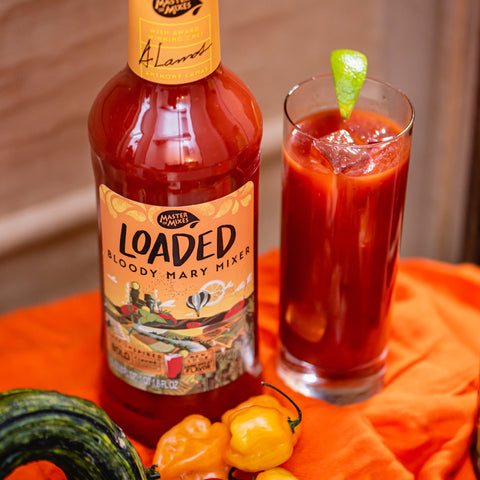 1L bottle of Master Of Mixes Loaded Bloody Mary Mixer with award-winning chef Anthony Lamas next to a bloodymary cocktail with a lime garnish.