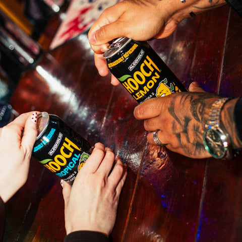 Two people opening two cans of Hooch, Hooch Tropical and Hooch Lemon, a premixed ready to drink alcopop. 