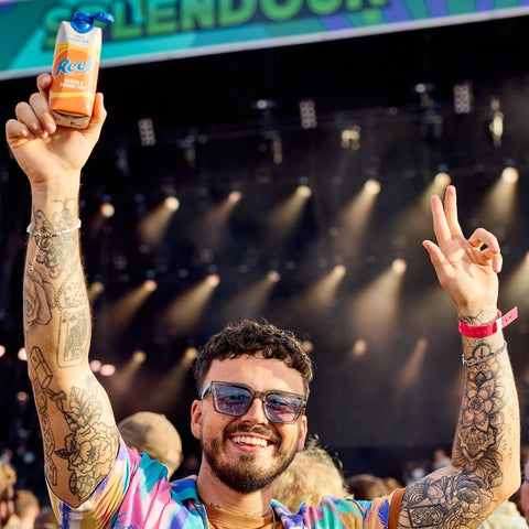 Someone at a festival holding a can of Reef premixed orange and passionfruit drink. 