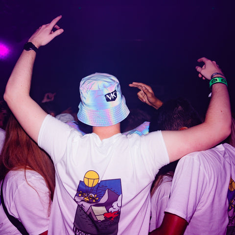 Party goer a reflective VK Bucket Hat while dancing in a nightclub with a VK branded wristband visible