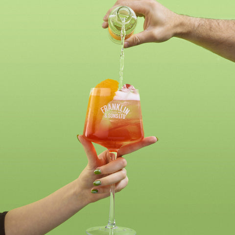 A Franklin & Sons glass with someone pouring a Franklin & Sons tonic into the glass as a mixer. 