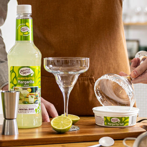 A person preparing a margarita glass by using Master of Mixes Margarita salt. 
