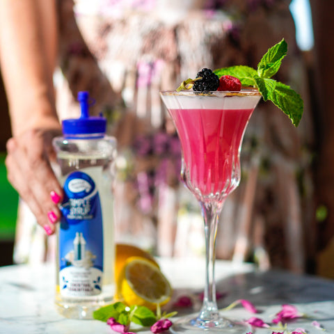 Someone making a cocktail using Master of mixes cocktail essentials simple syrup, perfect for making cocktails and mocktails. 