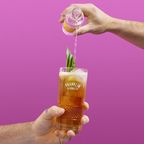 A Franklin & Sons glass with someone pouring a bottle of Franklin and Sons into the glass as a mixer 