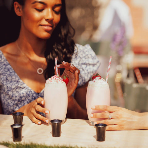 Two woman drinking alcoholic strawberry vegan milkshakes made with Lustre Strawberry Cream Tequila, a vegan cream liqueur. 
