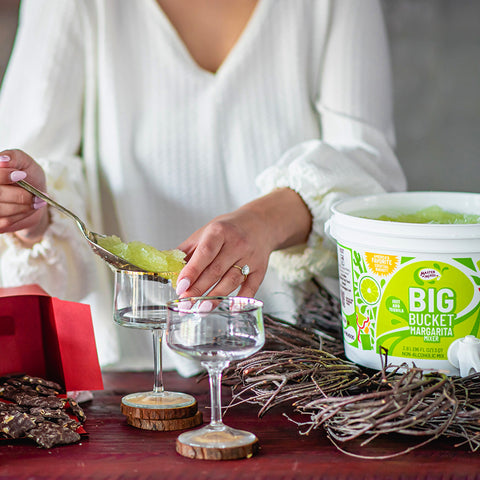 Master Of Mixes Big Bucket Margarita with a person serving the mix into a glass.