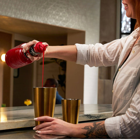 Finest Call Strawberry Puree Mix poured into a shaker at a bar