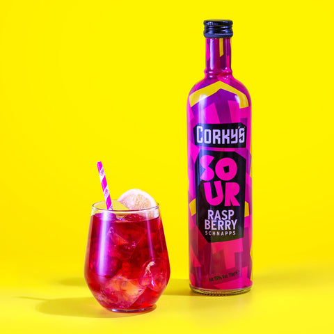 A bottle of Corky's sour raspberry schnapps next to a drink of raspberry schnapps and mixer on a bright yellow background. Corky's is an easy to shot & cocktail ingredient. 