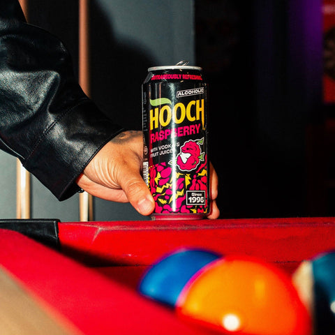 A person holding a can of Hooch Raspberry, a pink alcoholic lemonade, premixed and ready to drink. 