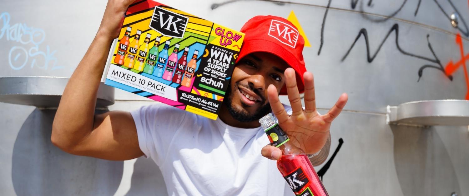 Good Time In | A man posing with a VK in his hand and a VK mixed pack in partnership with schuh