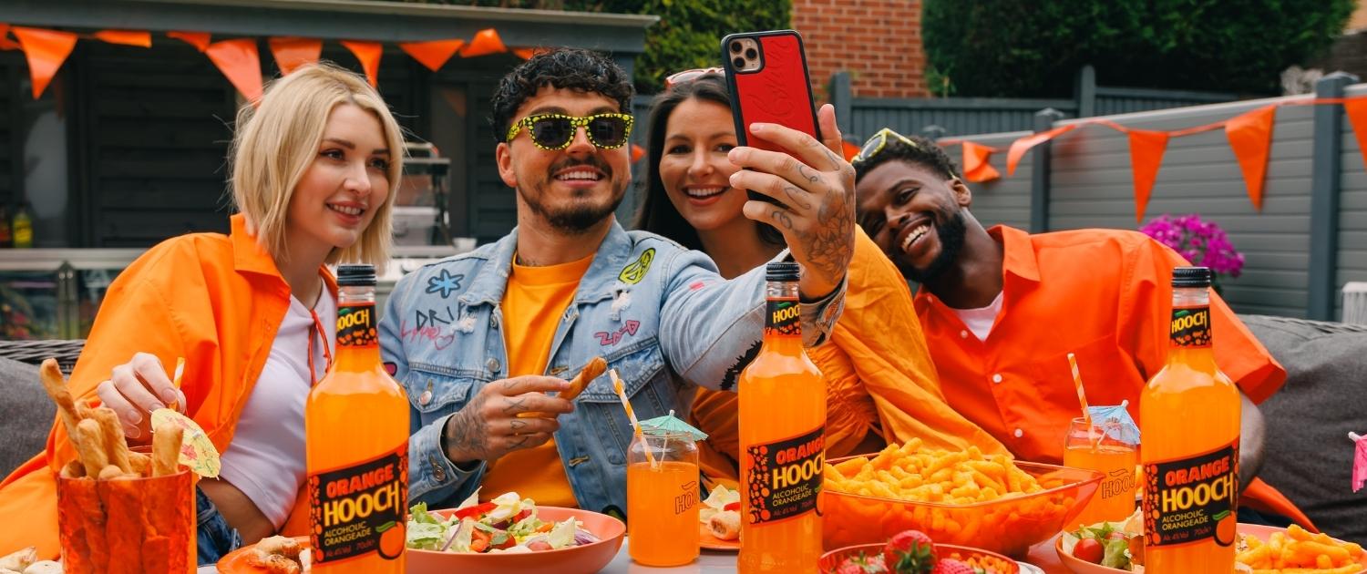 Good Time In | Four adults taking a selfie surrounded by all things orange for Orange Hooch